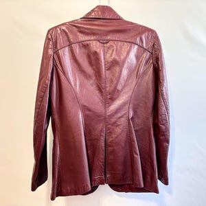 Pode incluir: Uma jaqueta de couro bord&ocirc; com um design cl&aacute;ssico. A jaqueta tem um acabamento liso e polido e uma silhueta ligeiramente ajustada.
