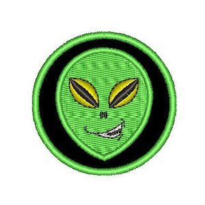 Può includere: Toppa ricamata raffigurante un volto alieno verde con occhi gialli e un sorriso furbo. L'alieno è inserito in un cerchio verde, incorniciato da un bordo nero, su sfondo bianco.
