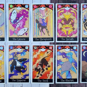 May include: Ten tarot cards featuring Pokemon characters. Each card has a different Pokemon and a tarot card name. The cards are on a wooden surface.