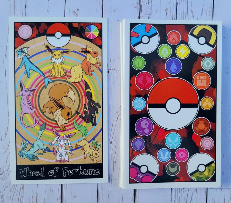May include: Two cards with a Pokemon theme. The first card features a colorful wheel with a Pokeball in the center and various Pokemon characters around the wheel. The text "Wheel of Fortune" is at the bottom of the card. The second card features a red and black background with a Pokeball in the center and various Pokemon symbols around the Pokeball.
