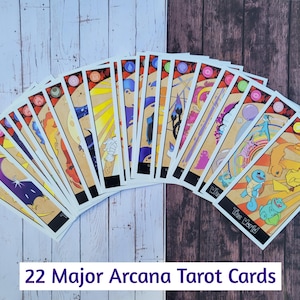 May include: A set of 22 Major Arcana Tarot cards featuring Pokemon characters. The cards are arranged in a fan shape, with the backs of the cards facing the viewer. The cards are colorful and feature various Pokemon characters, including Pikachu, Charizard, and Squirtle.