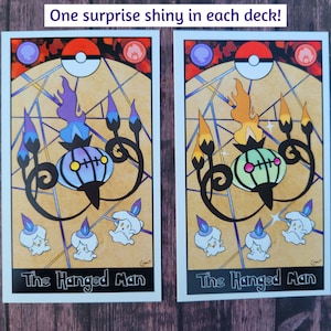 May include: Two tarot cards featuring the "The Hanged Man" card with a Pokemon illustration. The card on the left features a purple and blue Chandelure, while the card on the right features a green and yellow Chandelure.