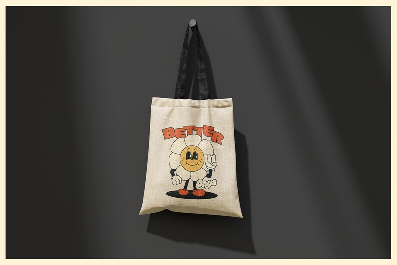 Pu&ograve; includere: Una borsa tote beige con manici neri. La borsa ha un fiore di cartone animato con un viso sorridente e le parole "Better Days" stampate su di essa.
