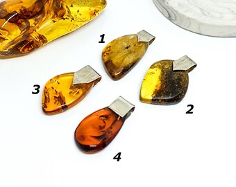 May include: Four amber pendants with silver bail settings. The pendants are in various shapes and colors, including yellow, orange, and brown.