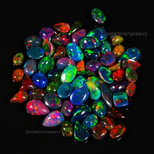 May include: A collection of iridescent opal gemstones in various shapes and sizes. The opals display a rainbow of colors, including green, blue, red, and purple.