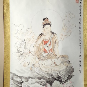 Può includere: Un dipinto tradizionale cinese su rotolo che raffigura una divinità femminile seduta su una roccia con fiori di loto. La divinità indossa una veste bianca con una fascia rossa e una corona. Lo sfondo è un cielo azzurro con nuvole. Il rotolo è montato su un bastone di legno e ha un bordo dorato.