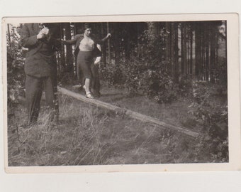 Instantánea inusual Un hombre enciende un cigarrillo mientras una joven camina sobre una viga Resumen Original instantánea vernácula Foto encontrada