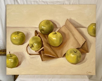 May include: A still life painting of green apples spilling out of a brown paper bag. The apples are arranged on a light beige surface. The painting is signed in the bottom right corner.