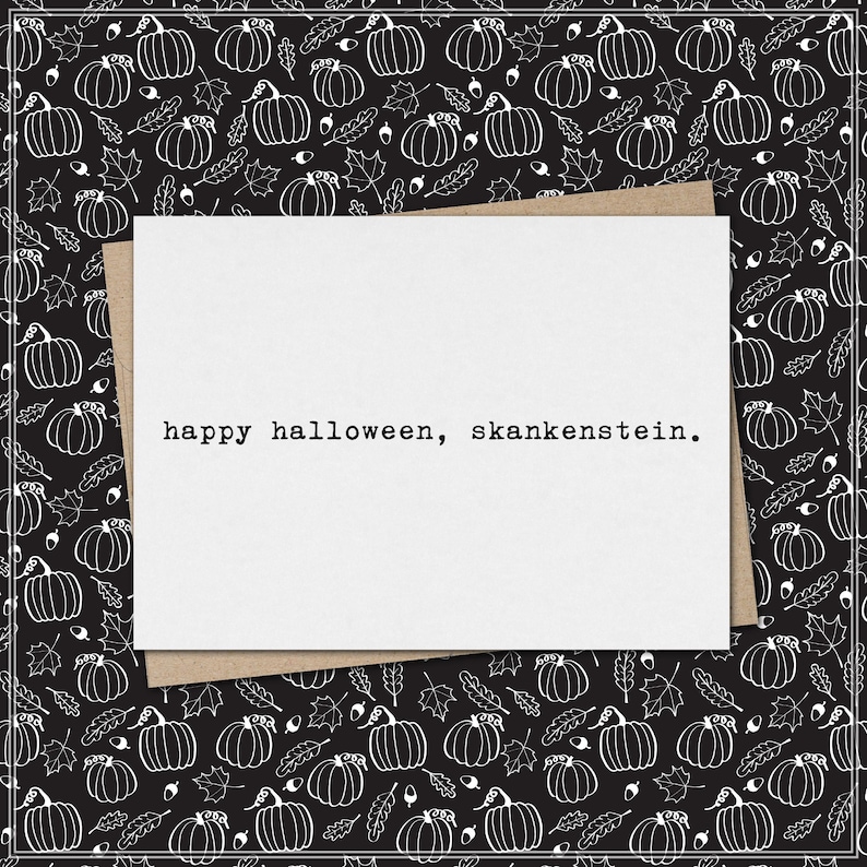 May include: A white rectangular greeting card with the black typewriter-style text "happy halloween, skankenstein." printed in the centre. The card is placed on a black background featuring a repeating white line-art pattern of pumpkins and leaves.