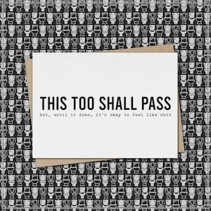 May include: A white greeting card with the text "THIS TOO SHALL PASS" and a humorous message. The card is on a brown envelope, set against a black and white toilet pattern background.