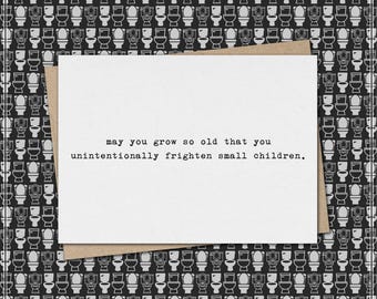 Puede incluir: Tarjeta de felicitación humorística con texto negro sobre fondo blanco: "may you grow so old that you unintentionally frighten small children." La tarjeta está sobre un sobre marrón, sobre un patrón de inodoros en blanco y negro.