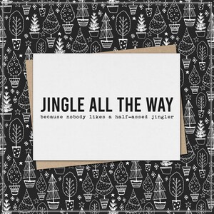 May include: A white greeting card with the text "JINGLE ALL THE WAY" and the phrase "because nobody likes a half-assed jingler." The card is on a brown envelope, with a black and white Christmas tree pattern background.