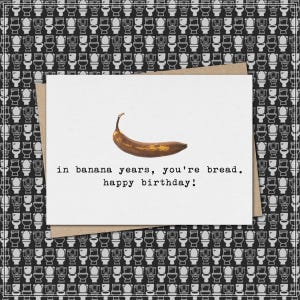 May include: A birthday card with a brown banana on a white background. The card reads "in banana years, you're bread. happy birthday!" The card is on a brown envelope, with a black and white toilet pattern background.