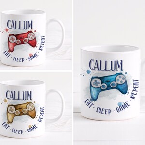 May include: White ceramic mug with a blue watercolour design of a video game controller and the text "CALLUM EAT-SLEEP-GAME-REPEAT".