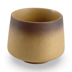 May include: A brown and tan ceramic teacup with a gradient glaze. The cup is wide at the top and tapers down to a narrow base.