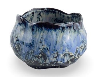 May include: A blue and white ceramic bowl with a wavy, irregular rim. The bowl has a marbled glaze with shades of blue, white, and black.