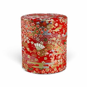 May include: Red cylindrical container with a floral pattern in gold, pink, and white. The container has a traditional Japanese design.