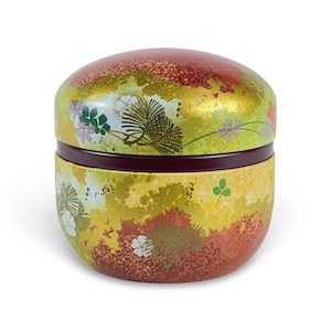 May include: A round, two-piece, red and gold lacquered box with a floral design. The box is decorated with a pattern of flowers, leaves, and branches. The lid of the box is slightly domed.