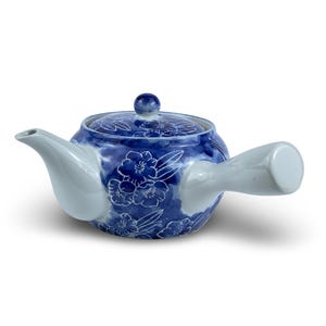 May include: A blue and white ceramic teapot with a floral design. The teapot has a single handle and a spout on the opposite side.