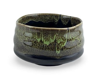 May include: A dark green and black ceramic tea bowl with a textured, speckled glaze. The bowl has a wide, rounded base and a slightly flared rim.