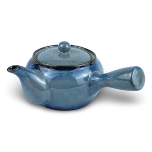 May include: A side-handled ceramic teapot featuring a glossy, deep blue glaze with a mottled texture. The teapot has a rounded body, a short spout, and a matching lid with a small knob handle. The side handle is thick and cylindrical in shape.
