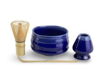 May include: A blue ceramic matcha bowl, a bamboo whisk, and a blue ceramic teacup. The set is used for preparing and drinking matcha tea.