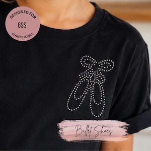 May include: A black t-shirt featuring a graphic of ballet shoes created with small white rhinestones on the chest. A circular badge in the upper left corner contains the text "DESIGNED FOR 6SS RHINESTONES" and a label reads "Ballet Shoes".