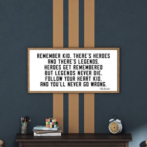 May include: A wooden framed print with a white background and black text. The text reads "REMEMBER KID. THERE'S HEROES AND THERE'S LEGENDS. HEROES GET REMEMBERED BUT LEGENDS NEVER DIE. FOLLOW YOUR HEART KID. AND YOU'LL NEVER GO WRONG."