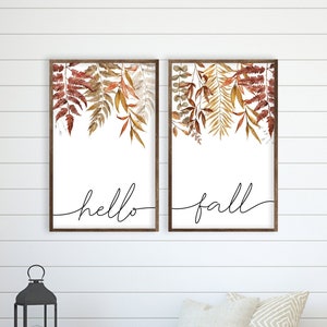 May include: Two framed prints with watercolor illustrations of autumn leaves. The prints have white backgrounds and black calligraphy that reads "hello fall".