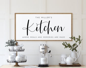 May include: A white sign with black text that reads "The Miller's Kitchen Where Meals and Memories Are Made". The sign is hanging on a white wall above a wooden countertop with a coffee maker, mugs, and other kitchen decor.