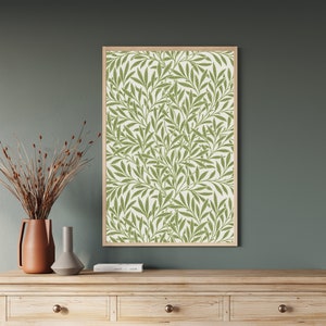 A framed print of a green and white floral pattern with a repeating design of leaves and branches. William Morris botanical wall art with green leaf pattern