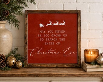 May include: A square wooden sign with a dark brown frame and a deep red background. The sign features a white graphic of Santa in a sleigh pulled by three reindeer above the text: MAY YOU NEVER BE TOO GROWN UP TO SEARCH THE SKIES ON Christmas Eve.