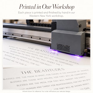 May include: A large industrial printer with a gray housing and purple UV light is printing black text onto a white surface. The text reads THE BEATITUDES followed by the biblical verses starting with Blessed are the poor in spirit.