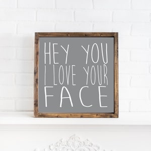 K&ouml;nnte beinhalten: Ein graues Holzschild mit einer wei&szlig;en Aufschrift, die "Hey you I love your face" lautet.
