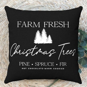 May include: Black throw pillow with white text that reads "Farm Fresh Christmas Trees Pine Spruce Fir Hot Chocolate Warm Cookies". The pillow features a white silhouette of three Christmas trees.