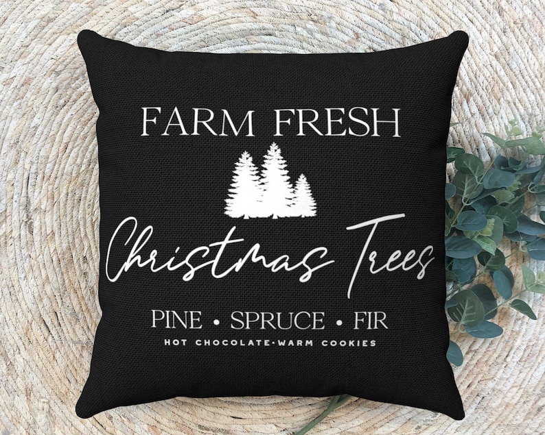 May include: Black throw pillow with white text that reads "Farm Fresh Christmas Trees Pine Spruce Fir Hot Chocolate Warm Cookies". The pillow features a white silhouette of three Christmas trees.