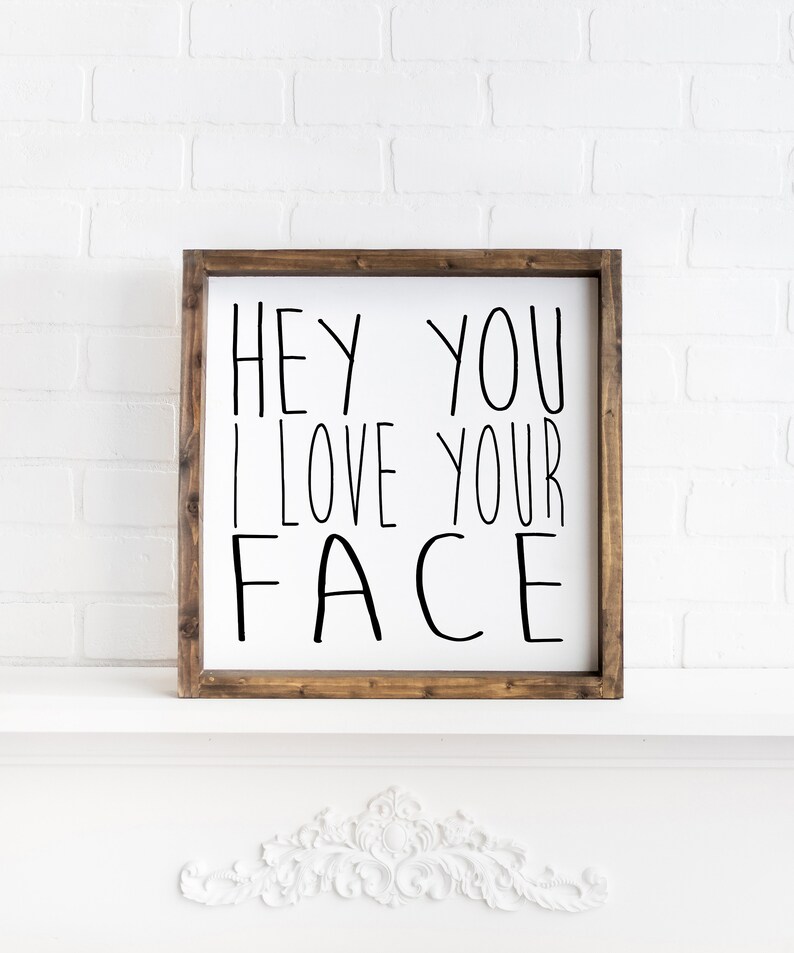 K&ouml;nnte beinhalten: Ein Holzschild mit dem Text "Hey You I Love Your Face" in schwarzen Buchstaben.