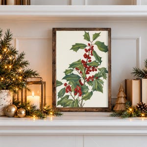May include: A framed botanical print featuring a detailed illustration of a holly branch with vibrant green, spiky leaves and clusters of bright red berries set against a plain, off-white background within a dark brown wooden frame.