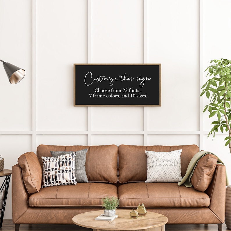 Pu&ograve; includere: Un'insegna da parete rettangolare con sfondo nero e una sottile cornice in legno. L'insegna presenta un testo bianco che recita: Customize this sign. Choose from 25 fonts, 7 frame colors, and 10 sizes. L'insegna &egrave; montata su una parete bianca.