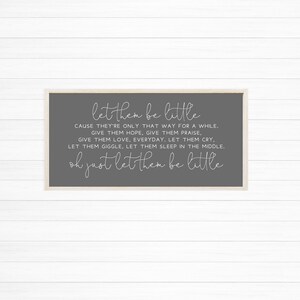 Op de afbeelding: Een rechthoekig wandbord met een lichthouten frame en een donkergrijze achtergrond. Het bord bevat witte tekst die luidt: let them be little, CAUSE THEY'RE ONLY THAT WAY FOR A WHILE. GIVE THEM HOPE, GIVE THEM PRAISE, GIVE THEM LOVE, EVERYDAY. LET THEM CRY, LET THEM GIGGLE, LET THEM SLEEP IN THE MIDDLE. oh just let them be little.