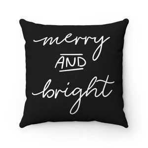 Puede incluir: Coj&iacute;n negro con texto blanco que dice "merry and bright".