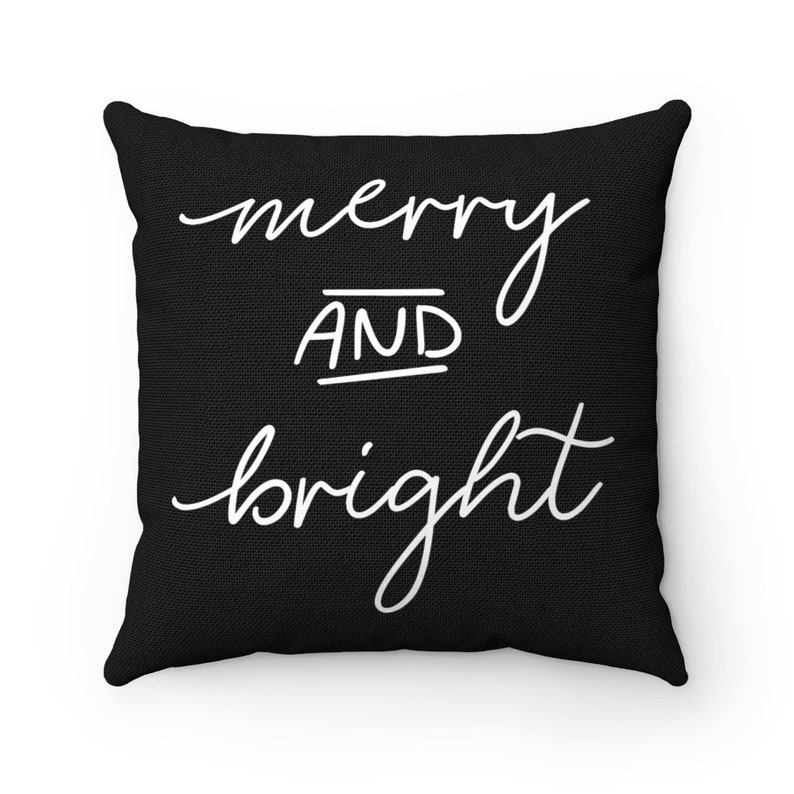 Puede incluir: Coj&iacute;n negro con texto blanco que dice "merry and bright".