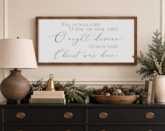 May include: A rectangular wall sign with a dark wood frame and a white background featuring black text that reads: FALL ON YOUR KNEES, O HEAR THE ANGEL VOICES, O night divine, O NIGHT WHEN Christ was born, in a mix of serif and script fonts.