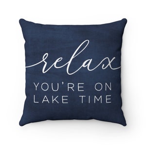 May include: Navy blue throw pillow with white text that reads "relax you're on lake time".