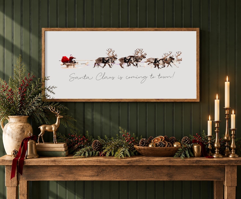Puede incluir: Un letrero de pared rectangular con marco de madera que muestra un gr&aacute;fico de Santa Claus en un trineo tirado por renos sobre un fondo blanco. El texto "Santa Claus is coming to town!" est&aacute; impreso en cursiva negra debajo.