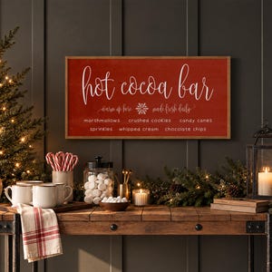 May include: A rectangular wooden sign with a red background and white text that reads Hot Cocoa Bar, warm up here, made fresh daily, and lists toppings including marshmallows, crushed cookies, candy canes, sprinkles, whipped cream, and chocolate chips.