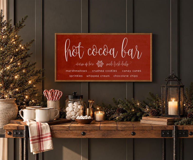 May include: A rectangular wooden sign with a red background and white text that reads Hot Cocoa Bar, warm up here, made fresh daily, and lists toppings including marshmallows, crushed cookies, candy canes, sprinkles, whipped cream, and chocolate chips.