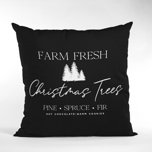 May include: Black throw pillow with white text that reads "Farm Fresh Christmas Trees Pine Spruce Fir Hot Chocolate Warm Cookies" and a graphic of three white Christmas trees.
