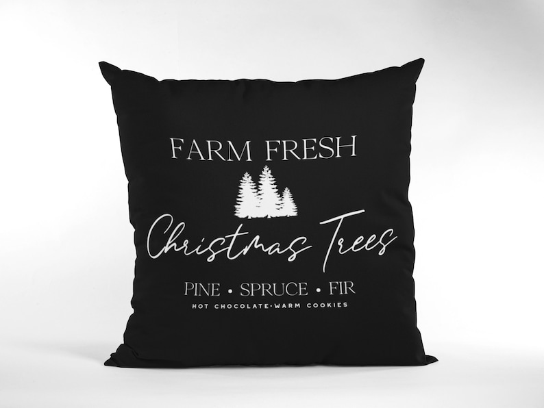 May include: Black throw pillow with white text that reads "Farm Fresh Christmas Trees Pine Spruce Fir Hot Chocolate Warm Cookies" and a graphic of three white Christmas trees.