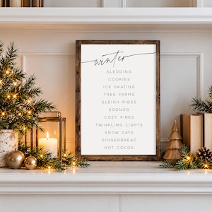 May include: A rectangular wooden sign with a dark brown frame featuring the word winter in black script at the top, followed by a list of words including sledding, cookies, ice skating, tree farms, sleigh rides, eggnog, cozy fires, and hot cocoa.